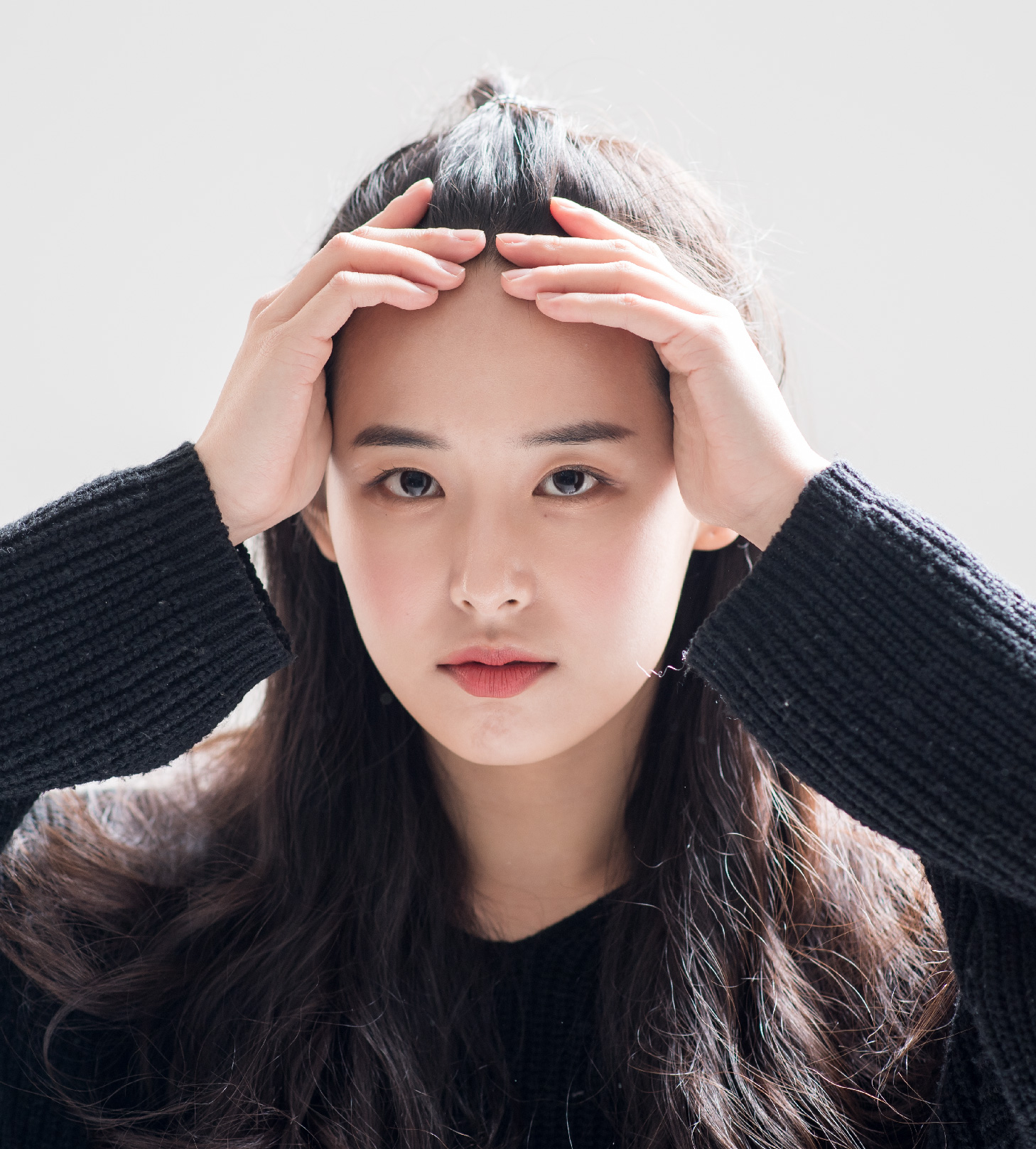 두 손으로 앞머리를 들어 올린 모델
