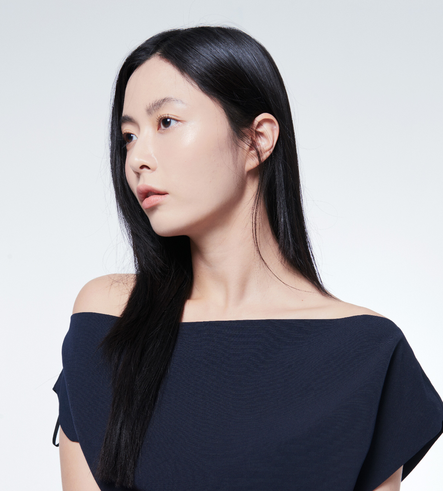 네이비 오프숄더 차림의 모델 옆얼굴